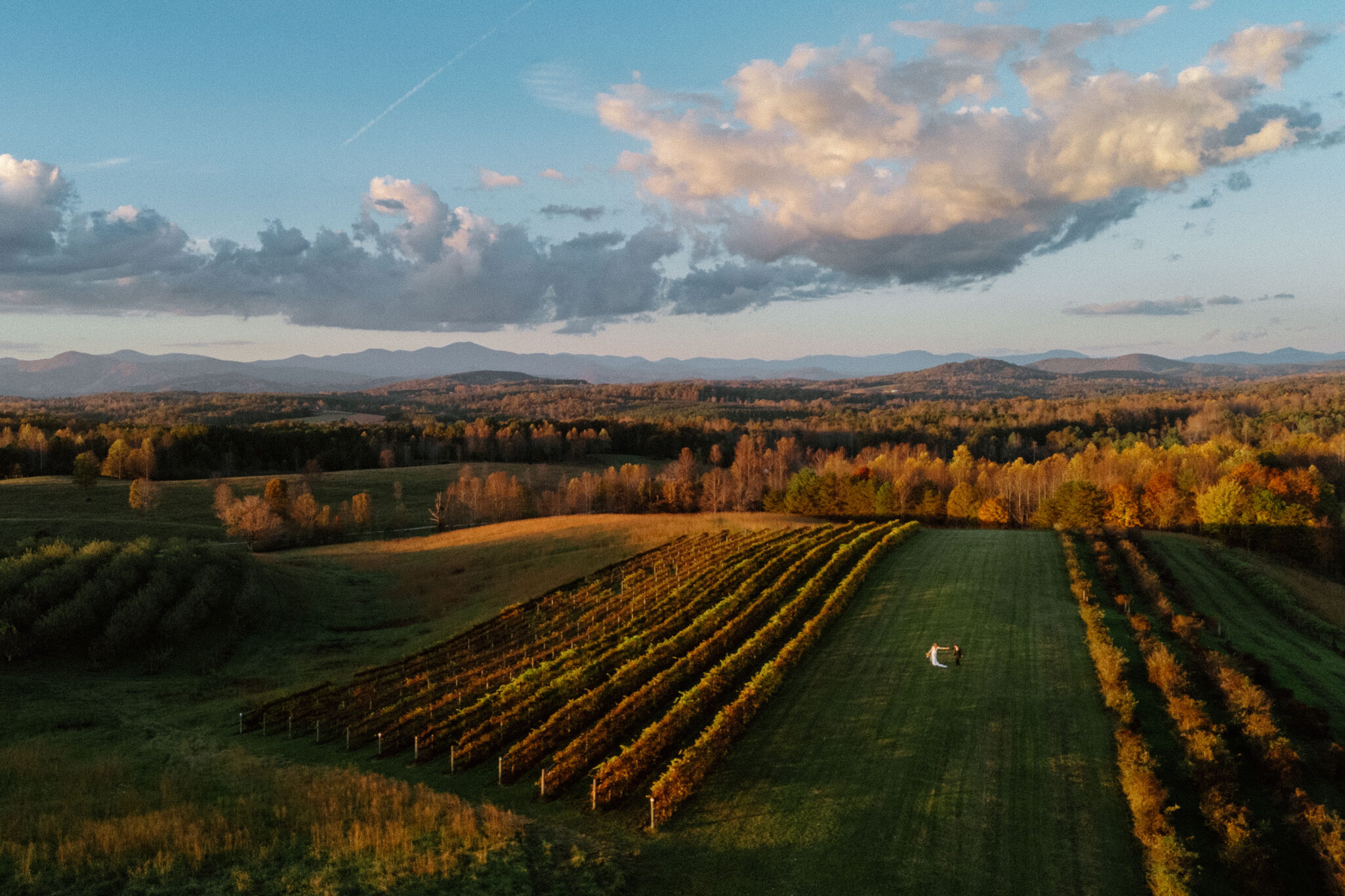 This photo is taken from a drone of a bride and Groom dancing in a field below.