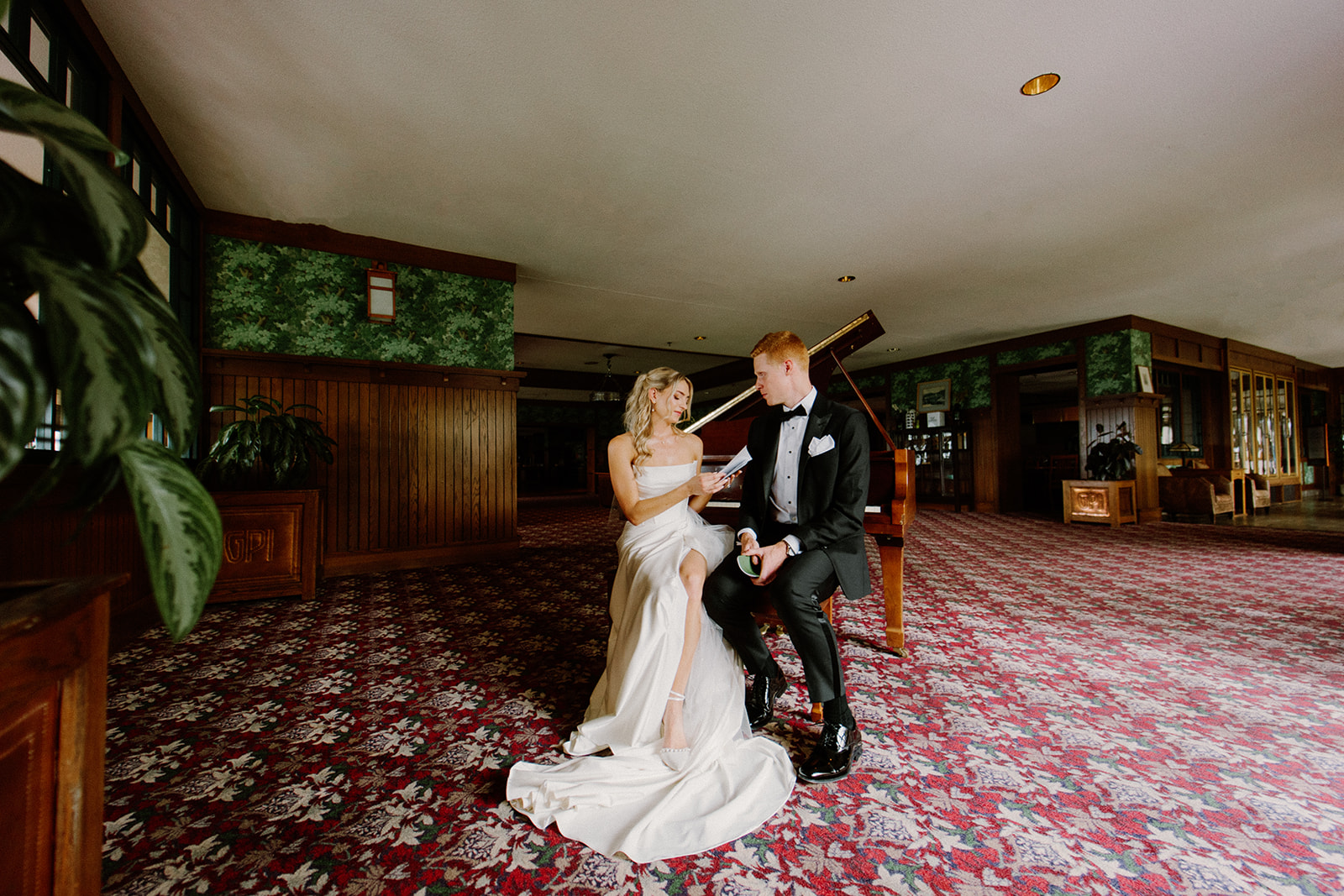 Bride and groom seated close together, holding green vow booklets and each other's hands, sharing an intimate moment before the ceremony at the Omni Grove Park Inn.