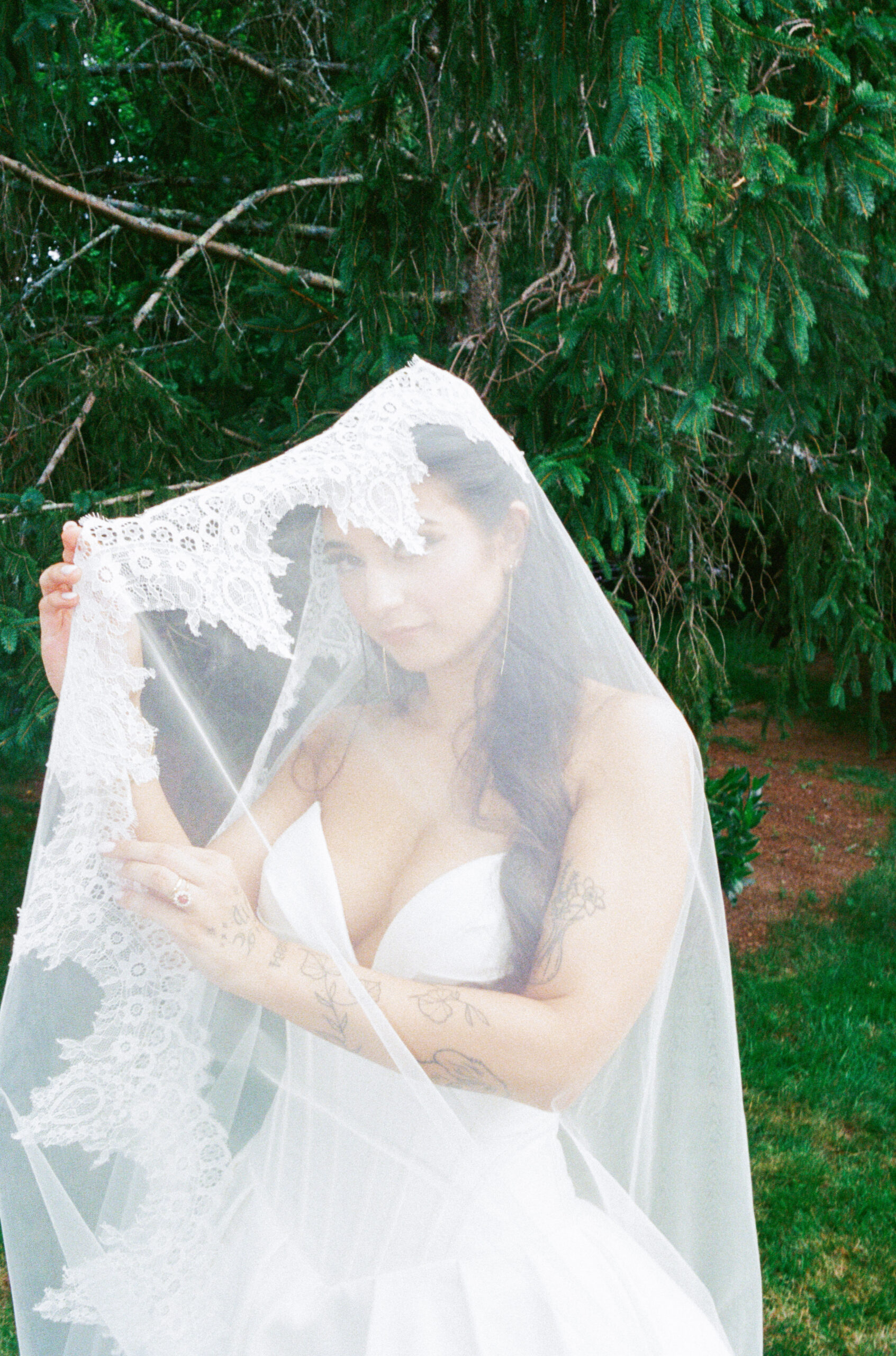 Bride holding a lace veil over her face in a soft 35mm film wedding portrait