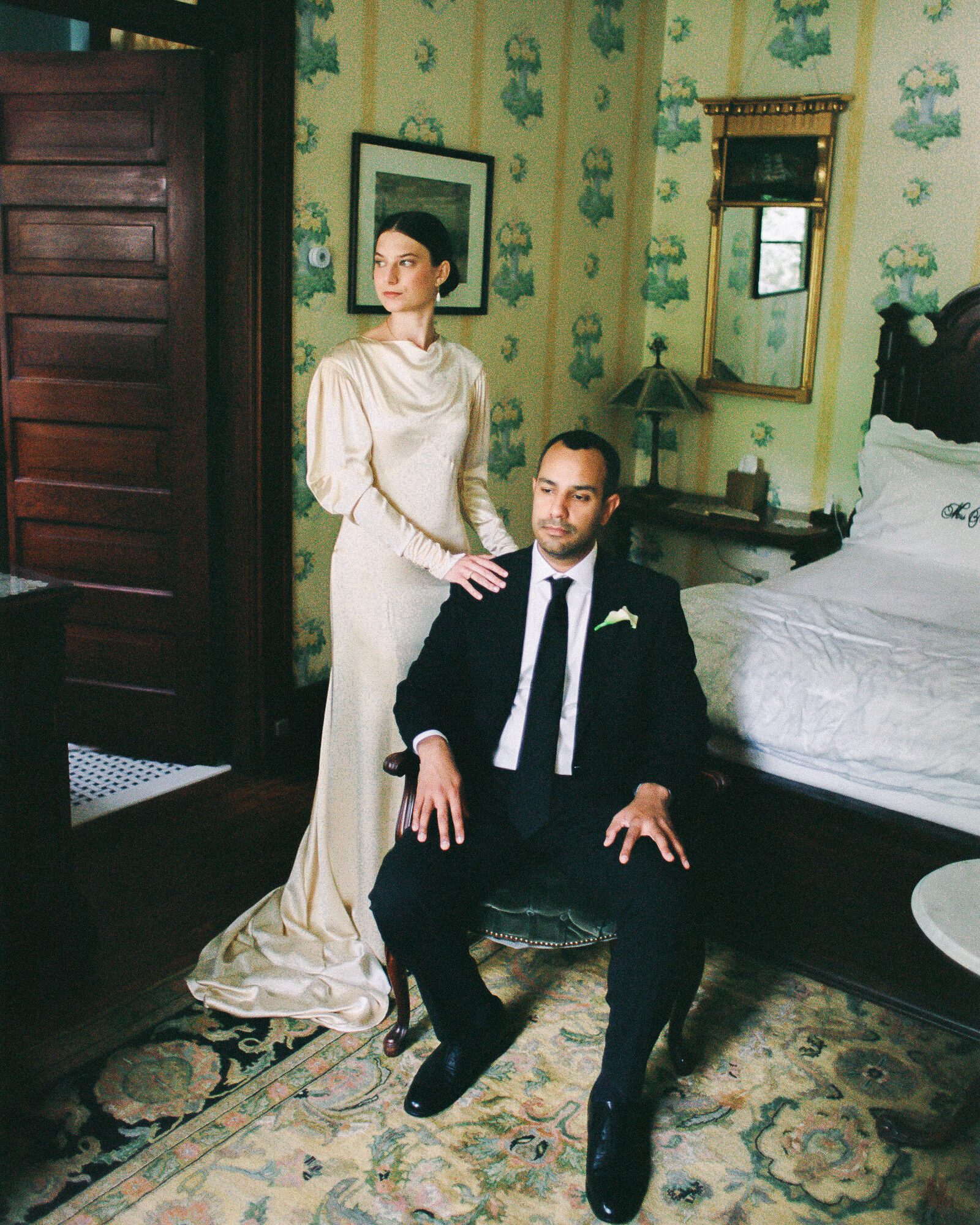 Editorial film wedding portrait of a couple in a vintage bedroom