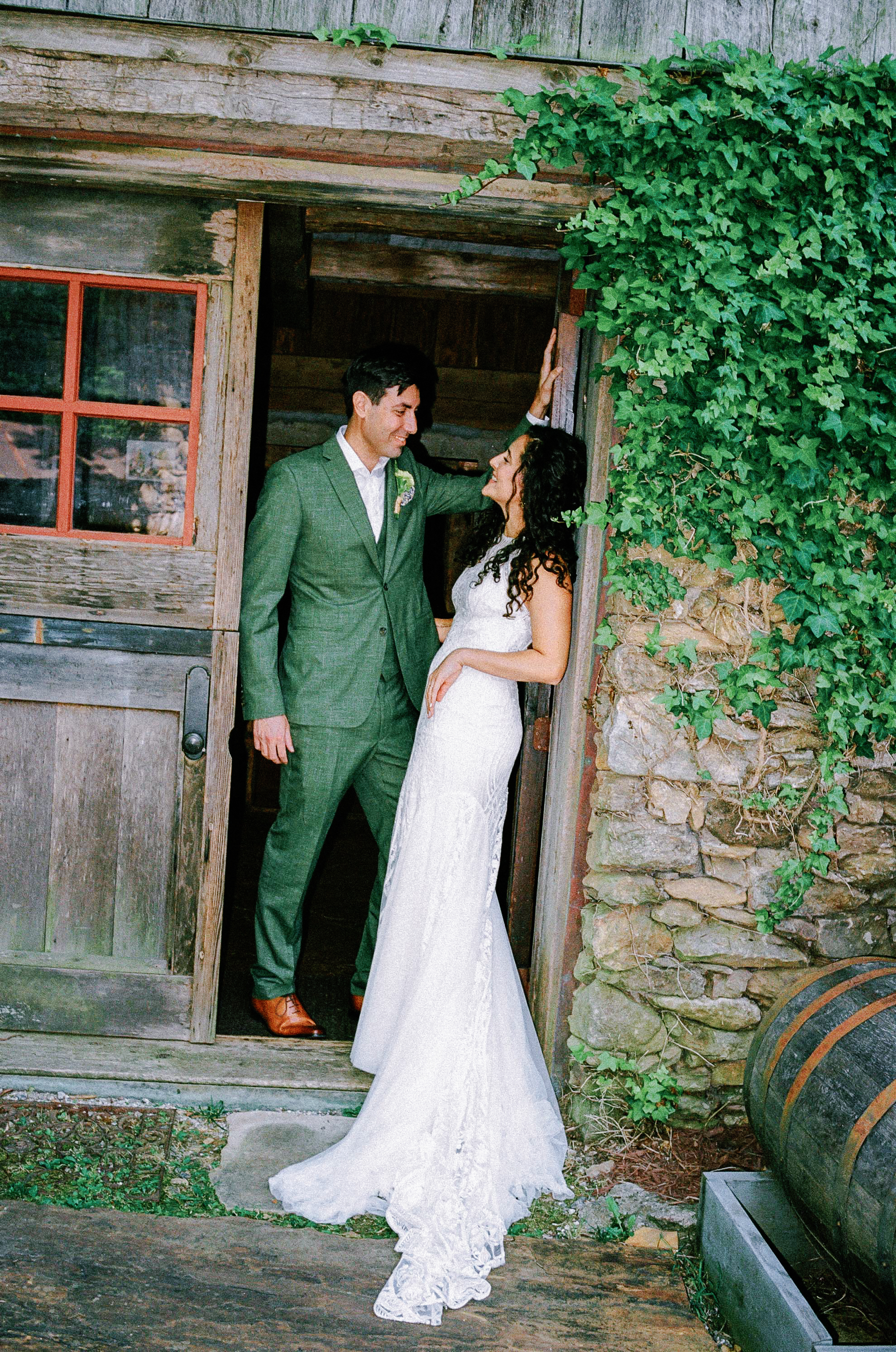 Bride and groom sharing a candid moment in the doorway of a rustic stone building