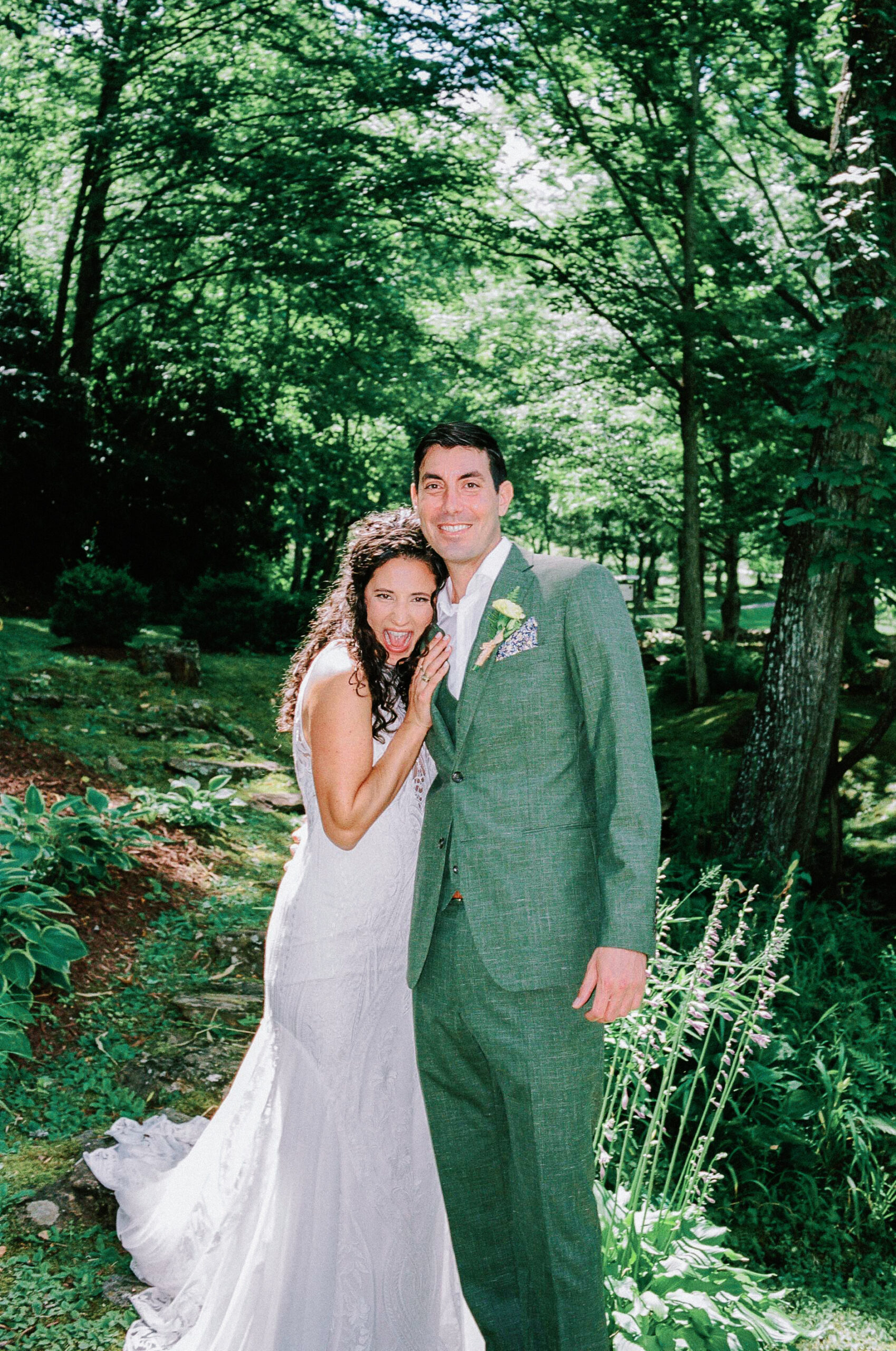 Bride and groom smiling together among the greenery at a Western North Carolina wedding