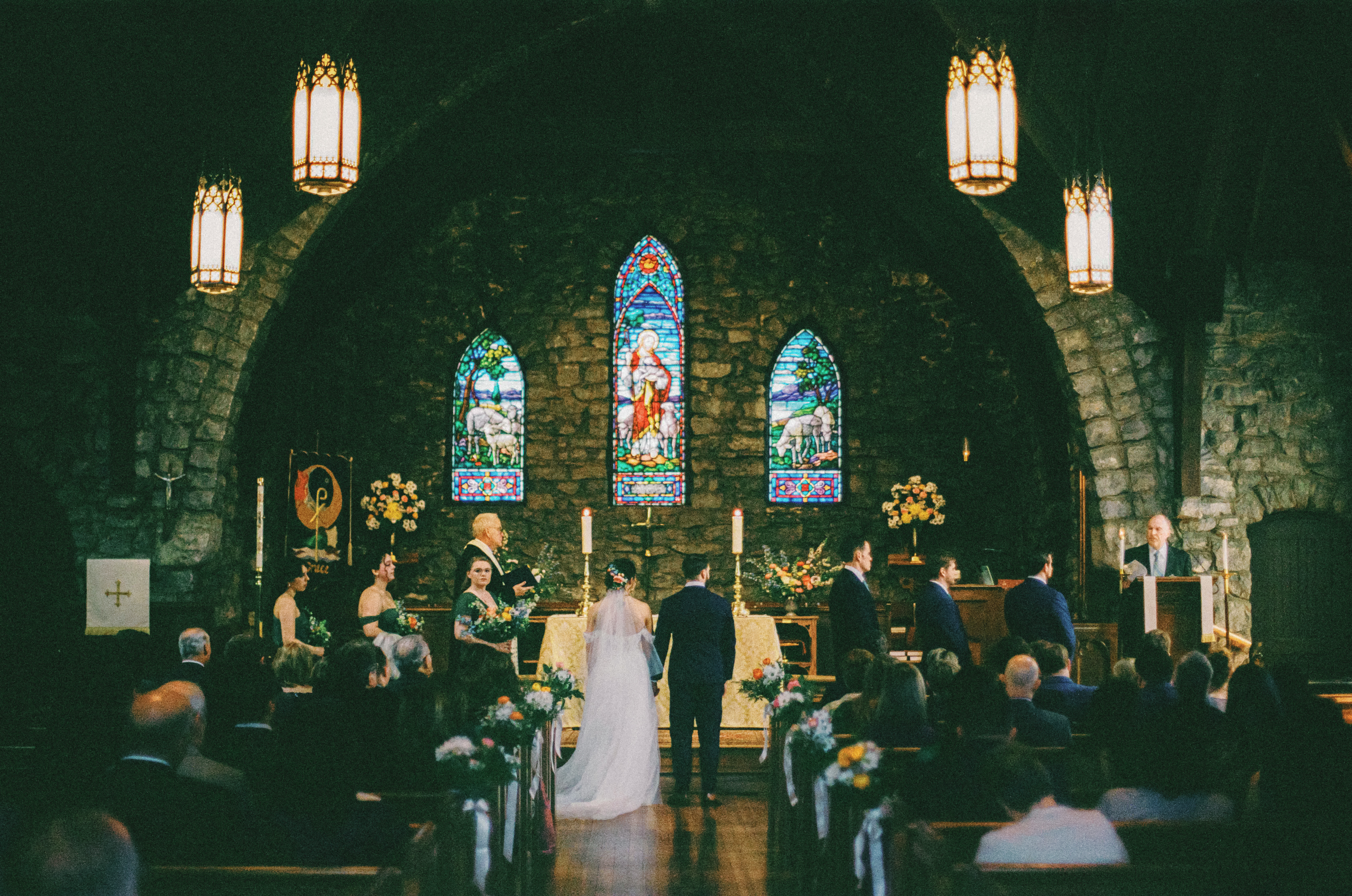 Wide film photograph of a wedding ceremony inside a historic Asheville chapel
