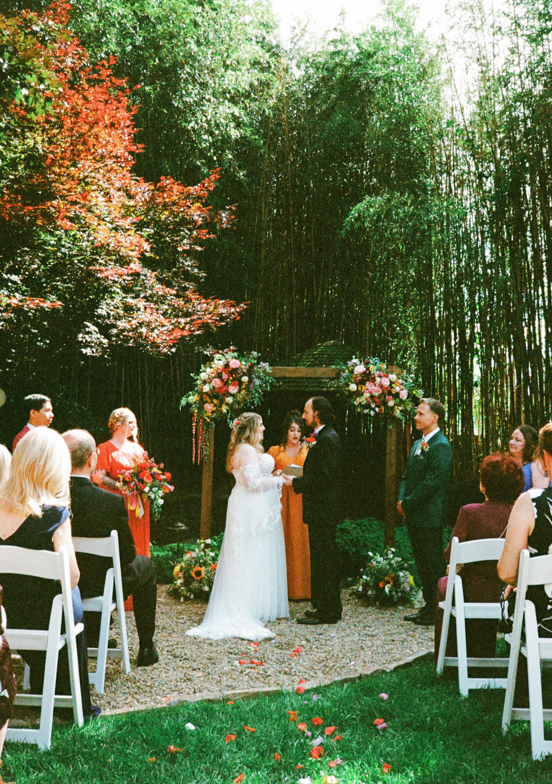 Outdoor wedding ceremony surrounded by lush greenery and colorful flowers