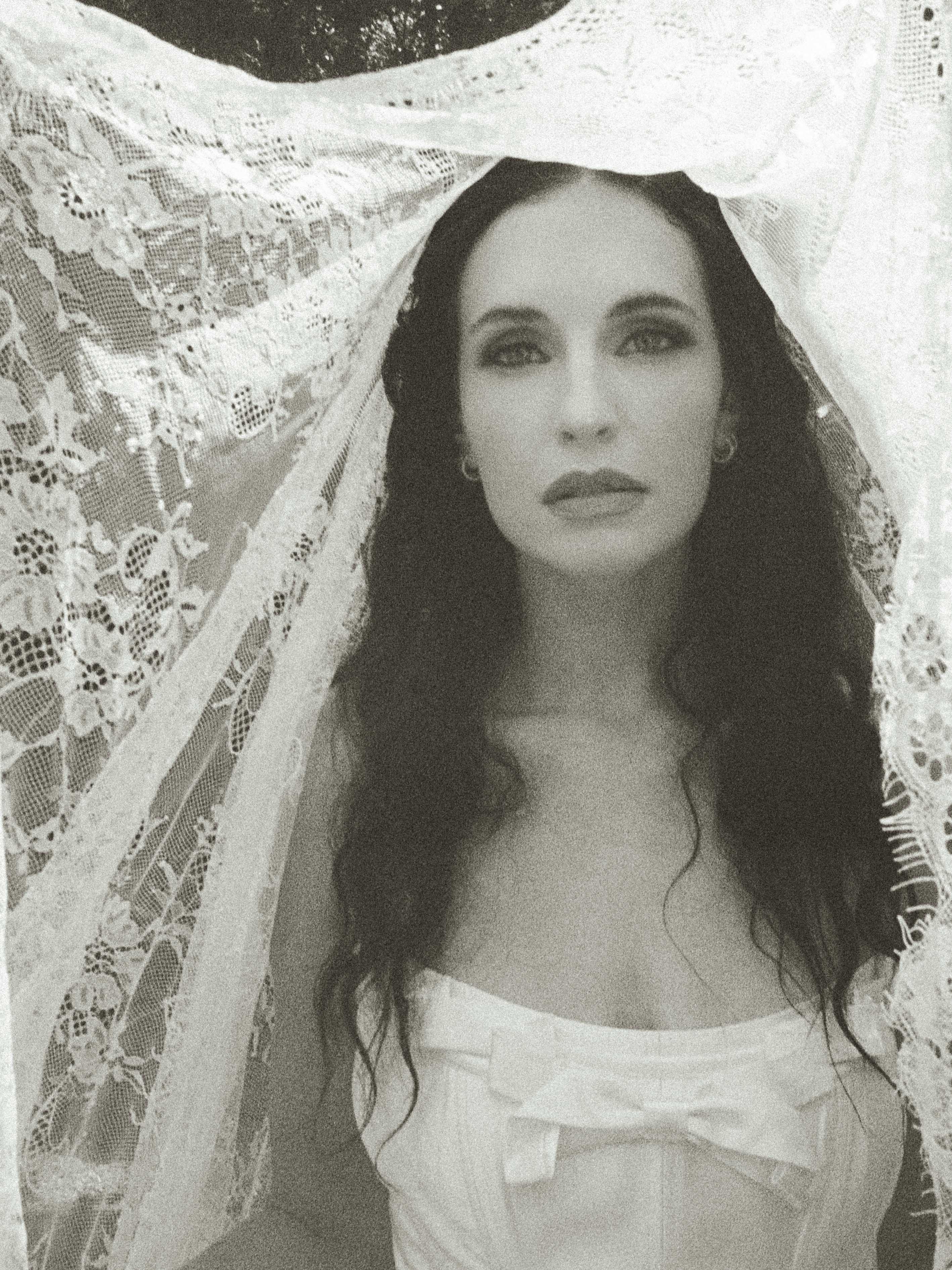 Black-and-white 35mm film portrait of a bride beneath her lace veil