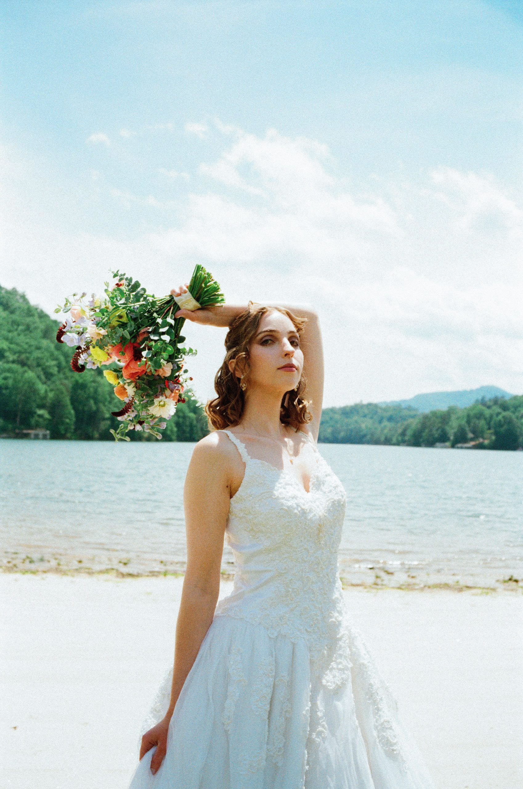 Editorial medium format film portrait of a bride beside a mountain lake