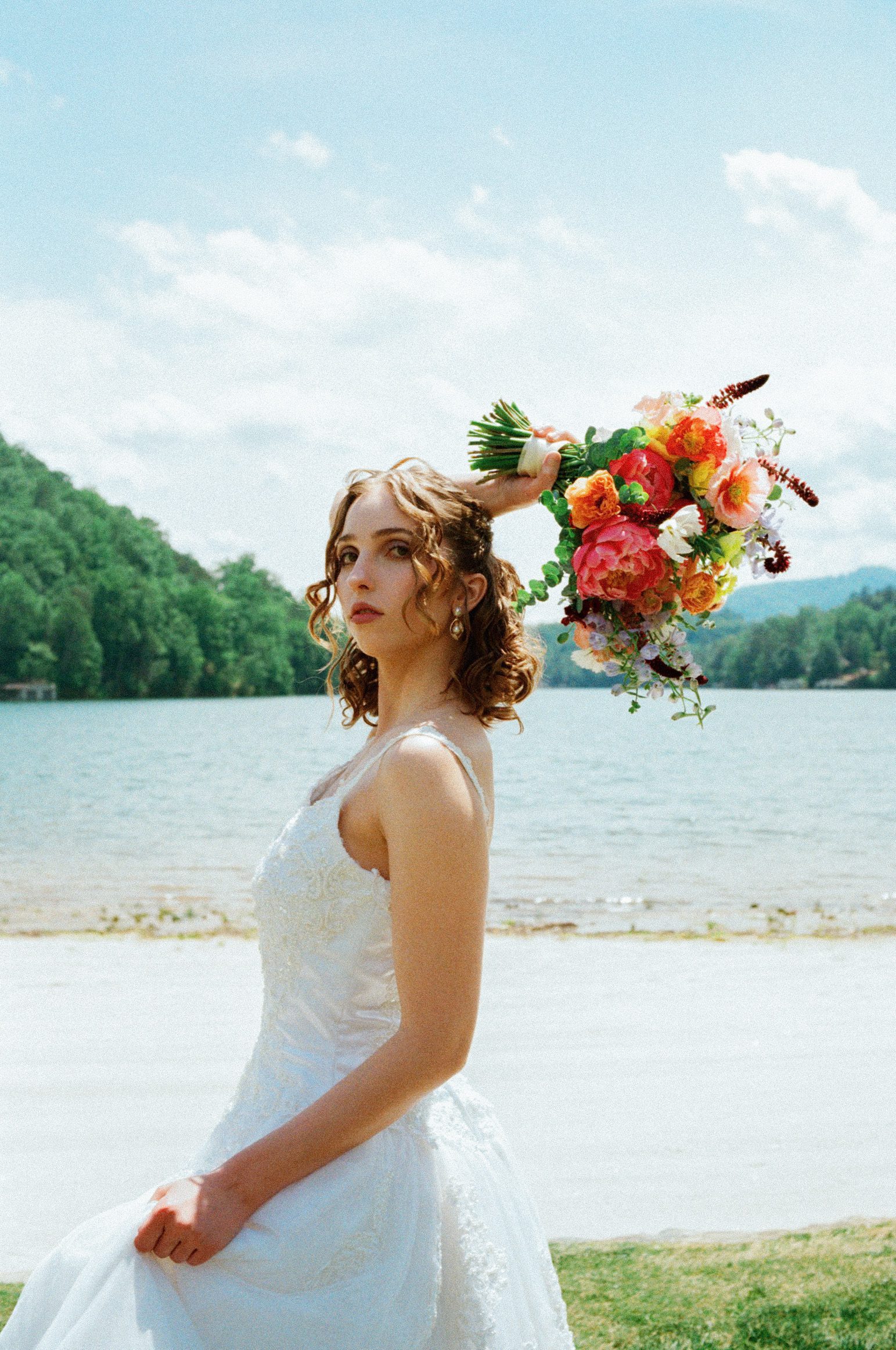 Bride holding a bright bouquet beside a mountain lake in Western North Carolina