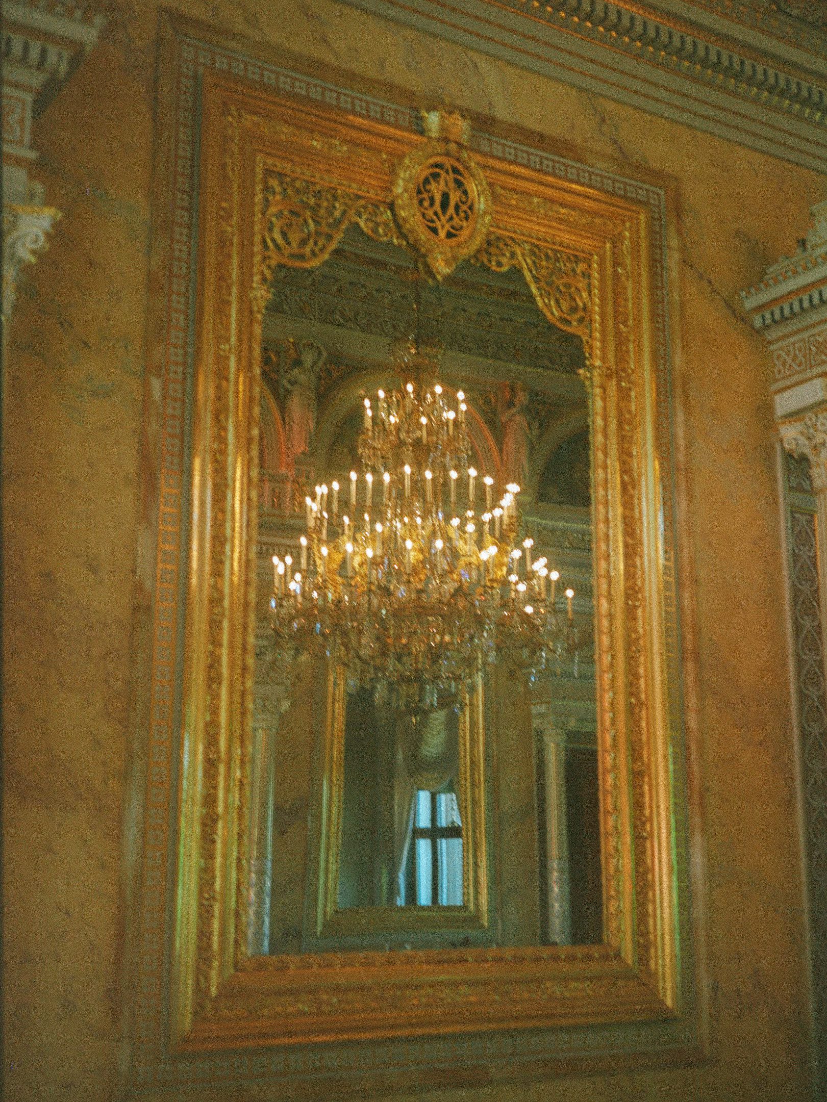 Ornate chandelier reflected in a gilded mirror at a wedding venue