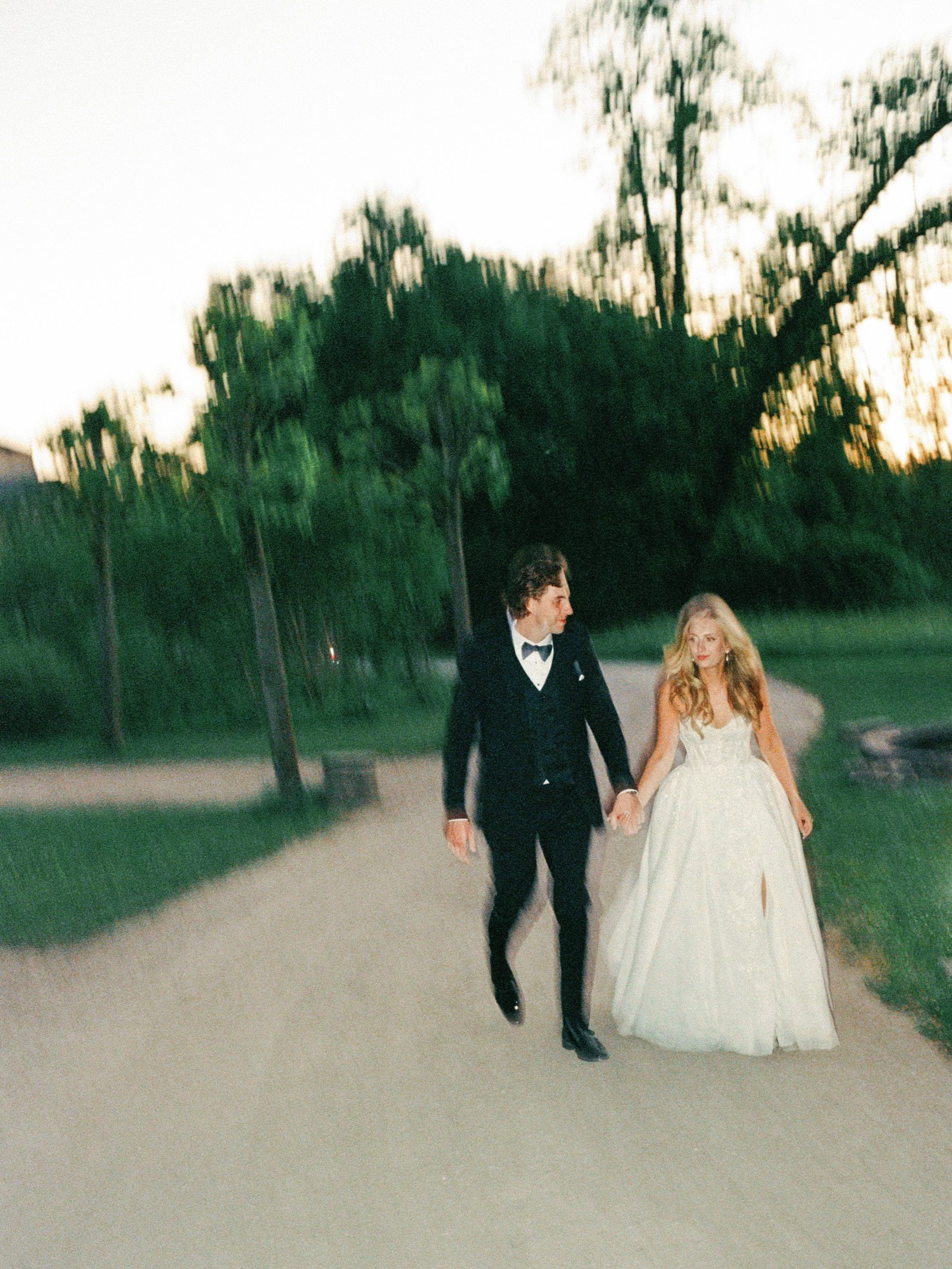 Newlyweds walking together at sunset in a softly blurred film photograph
