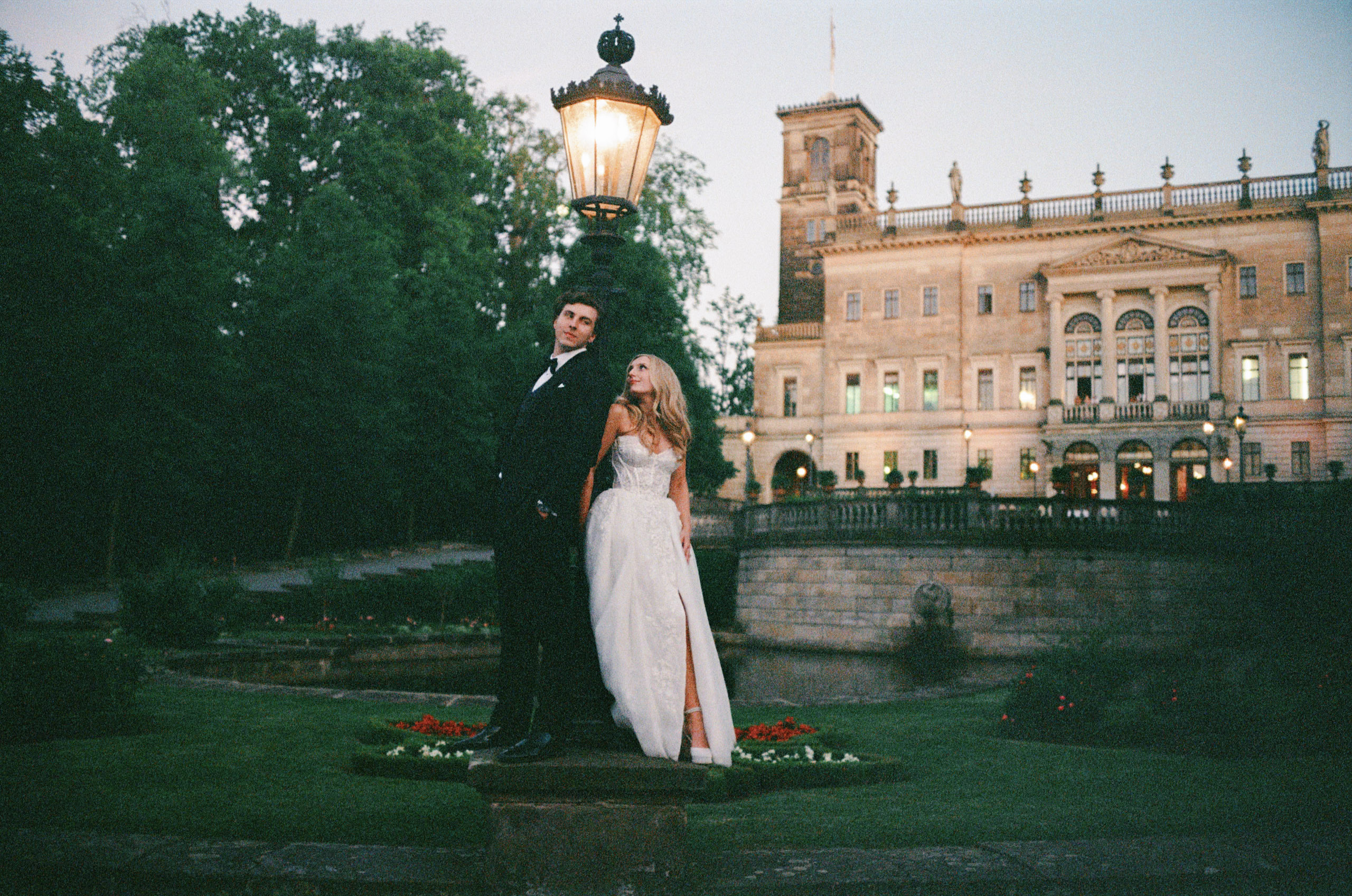 Newlyweds outside a grand historic estate in a horizontal film photograph