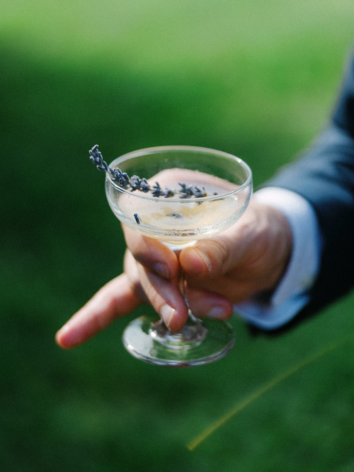 Lavender-garnished drink held by the groom