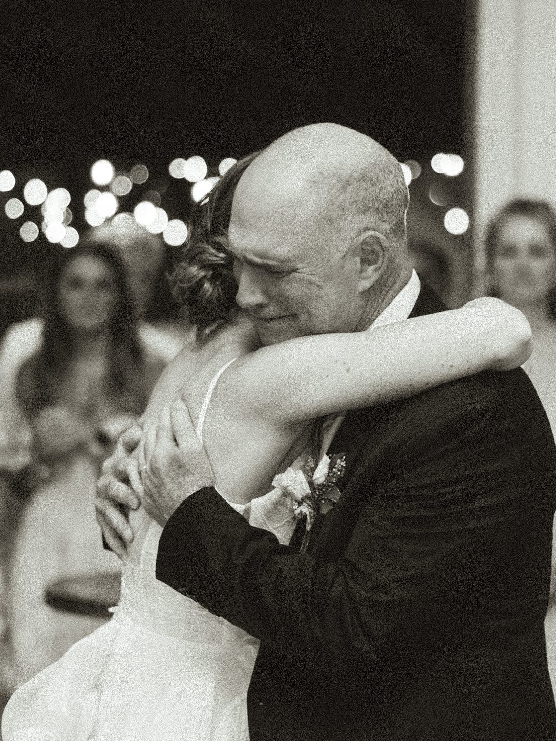 Black-and-white photograph of the bride embracing a guest