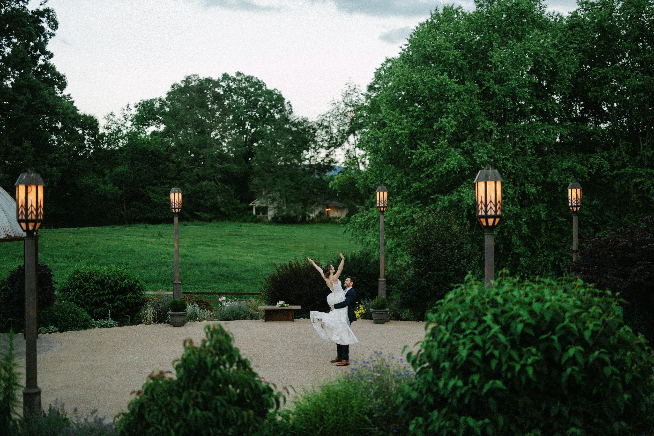 Groom lifting the bride outdoors near the lanterns