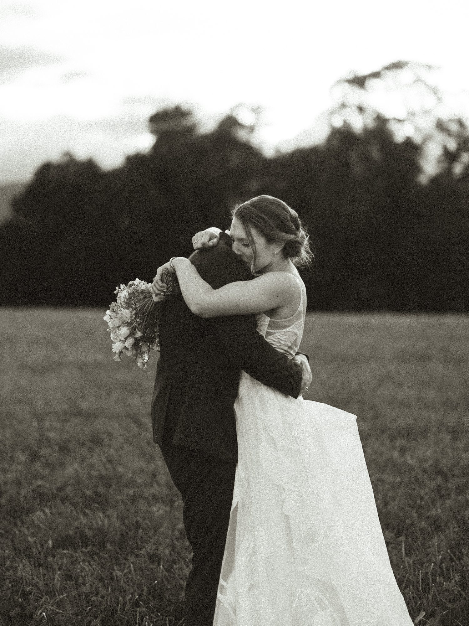 Black-and-white portrait of the couple embracing in a field