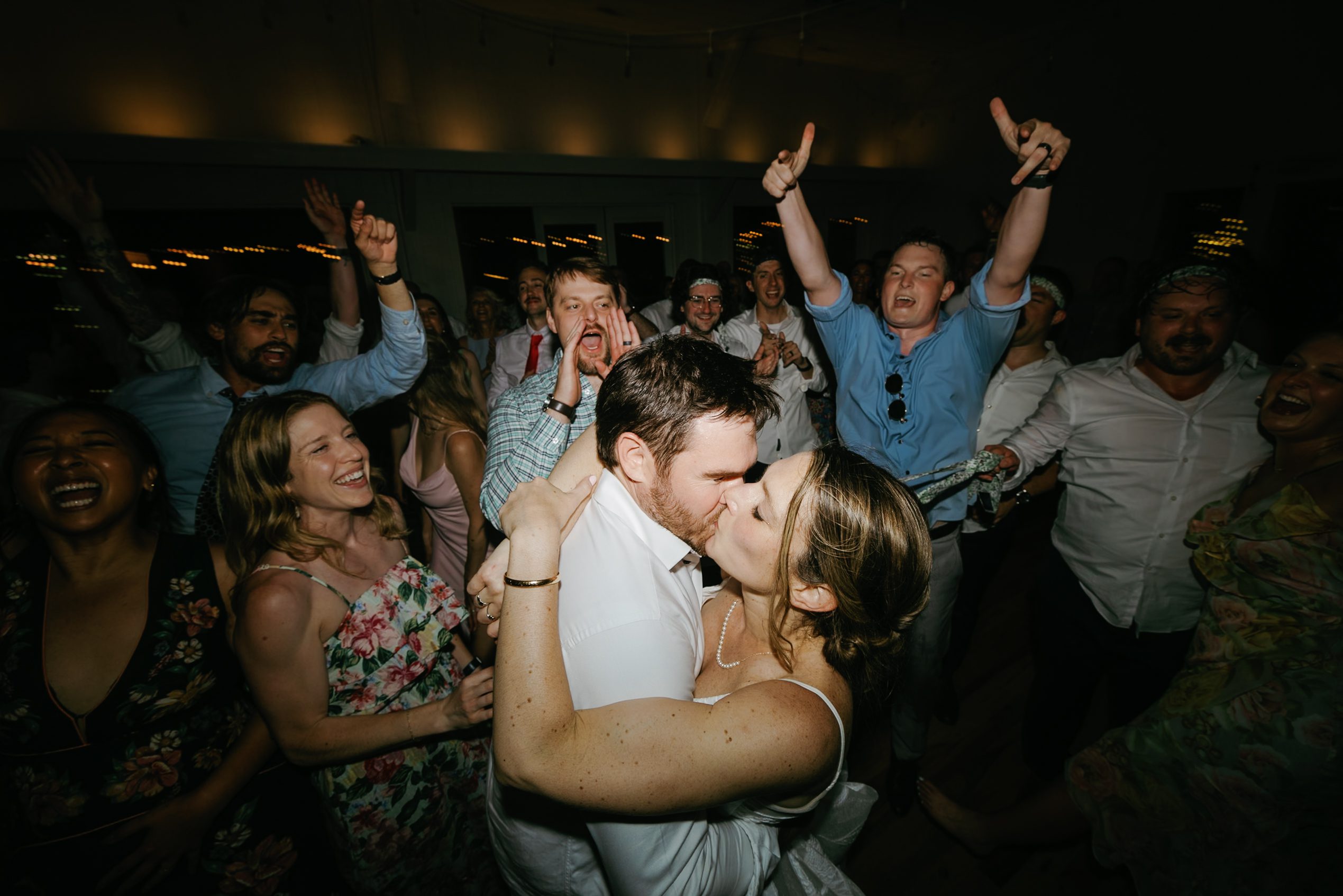 Newlyweds kissing amid cheering friends on the dance floor