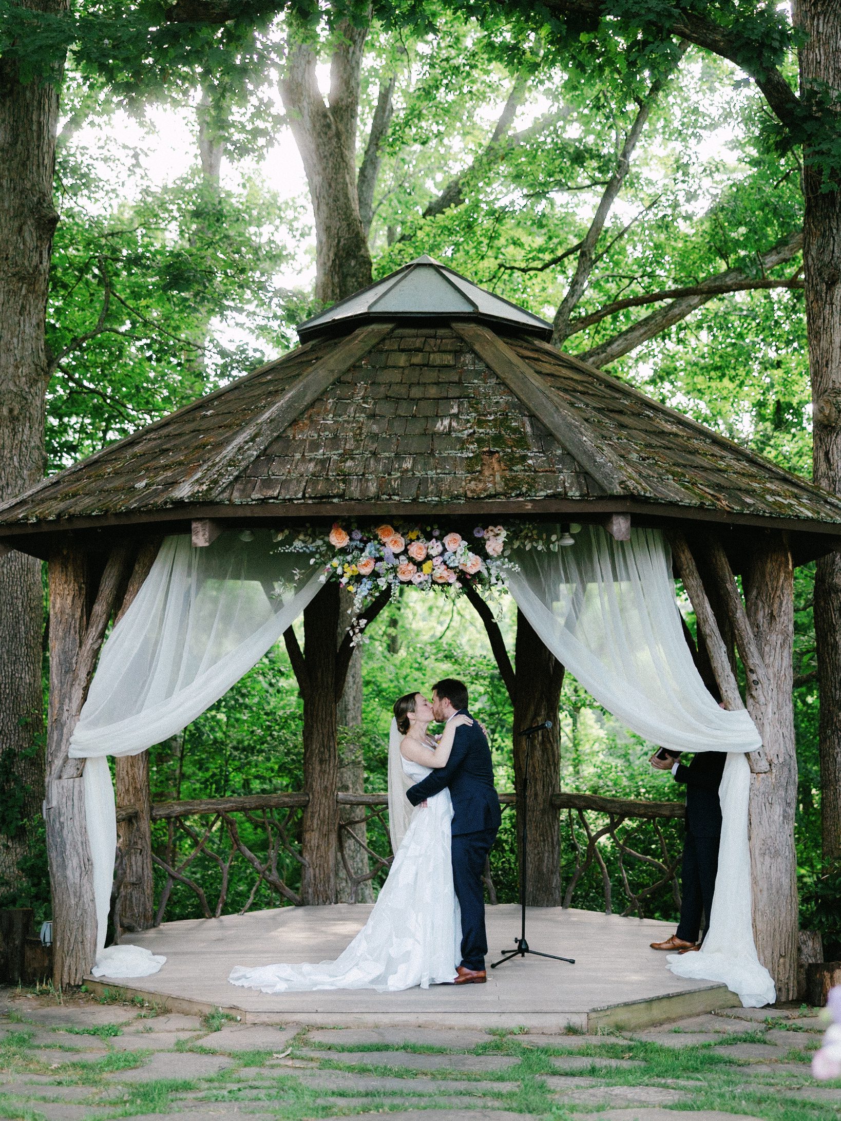 Wedding kiss beneath the flower-decorated wooden gazebo