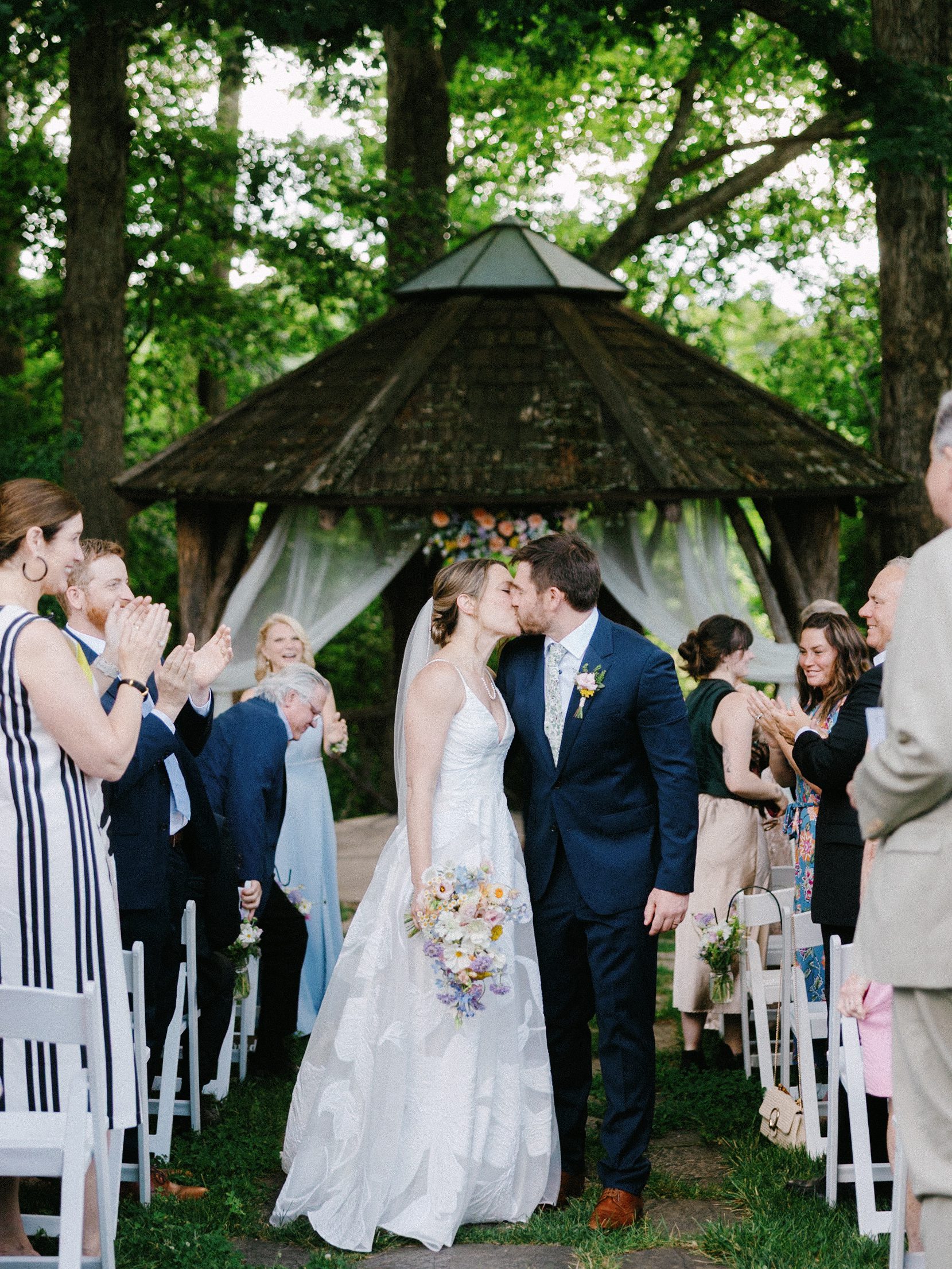 Newlyweds kissing in the aisle as guests applaud