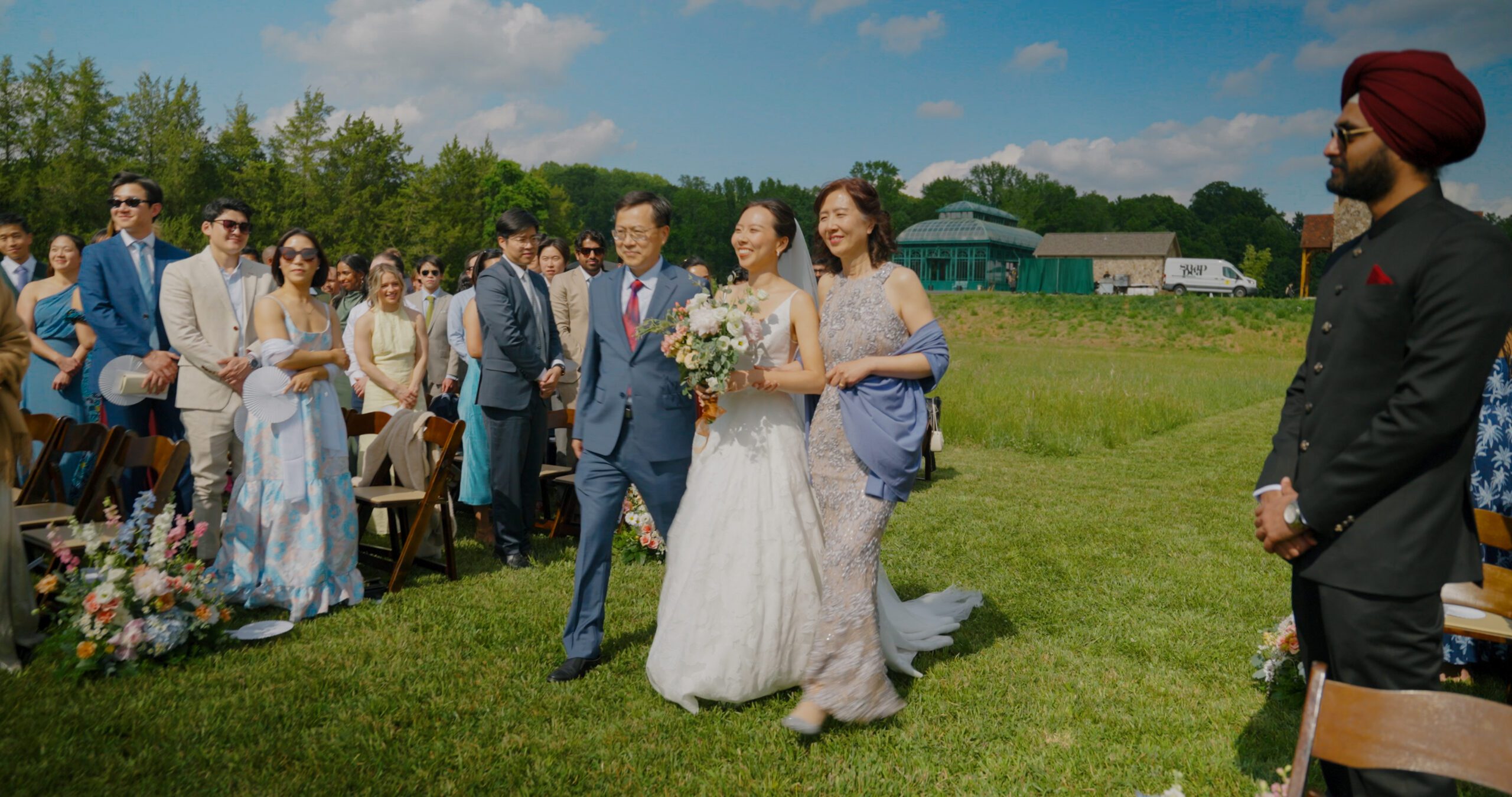 Christie walks down the meadow aisle with her family at The Little Chapel at Haven Ridge.
