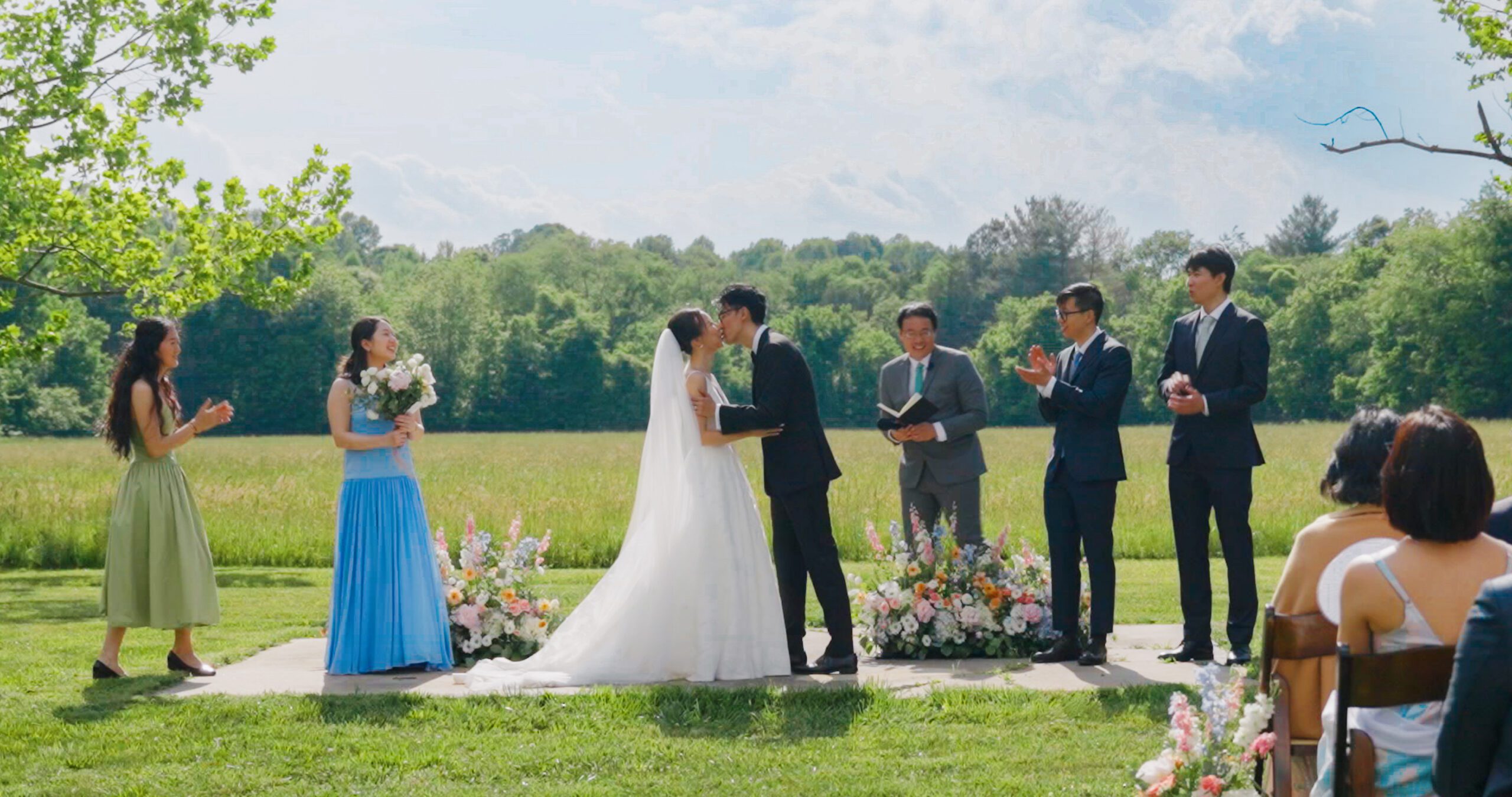 Christie and Hao exchange vows in the meadow at Haven Ridge, surrounded by their wedding party.