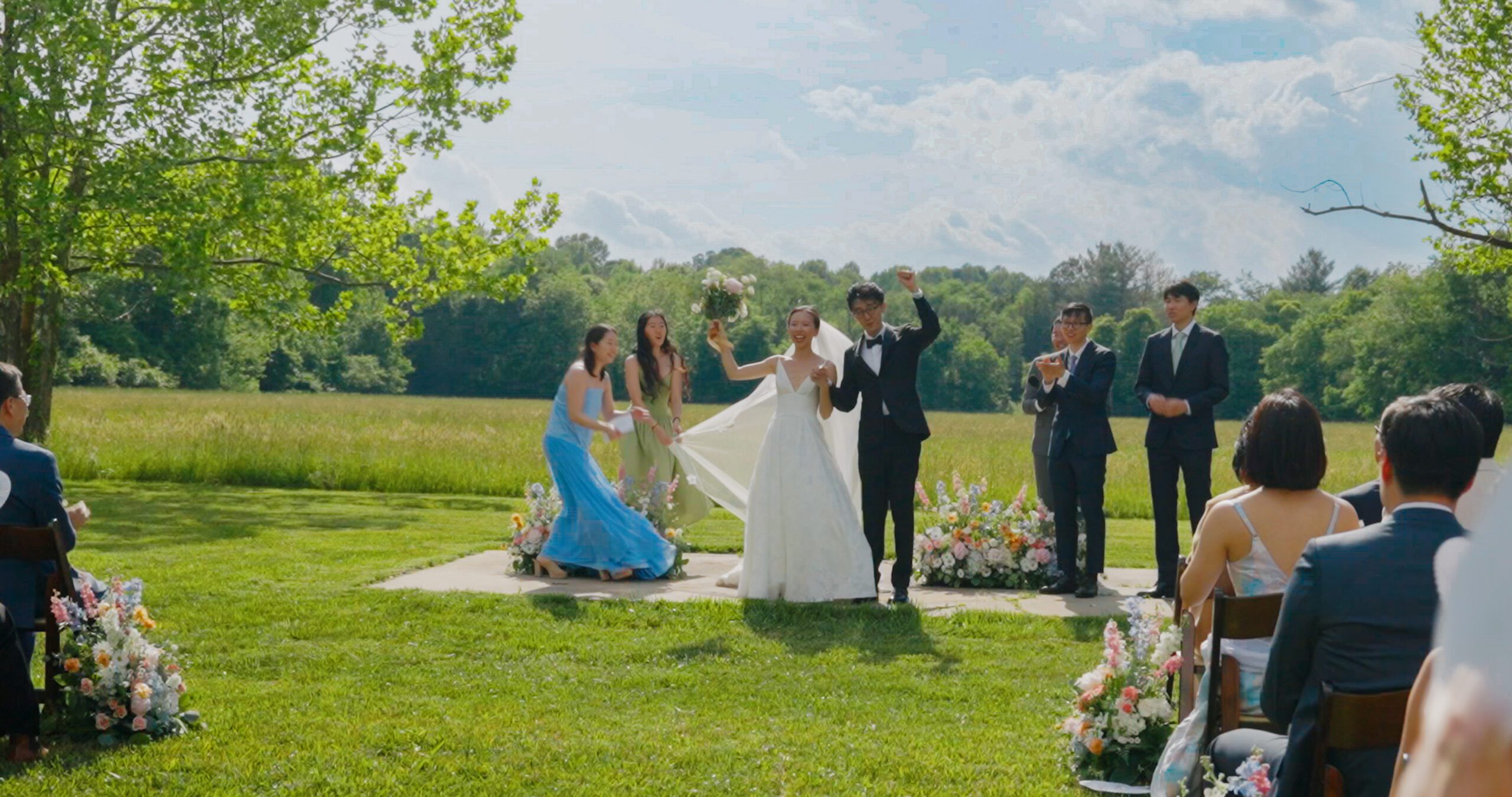 Guests watch Christie and Hao share a kiss during their meadow wedding ceremony.
