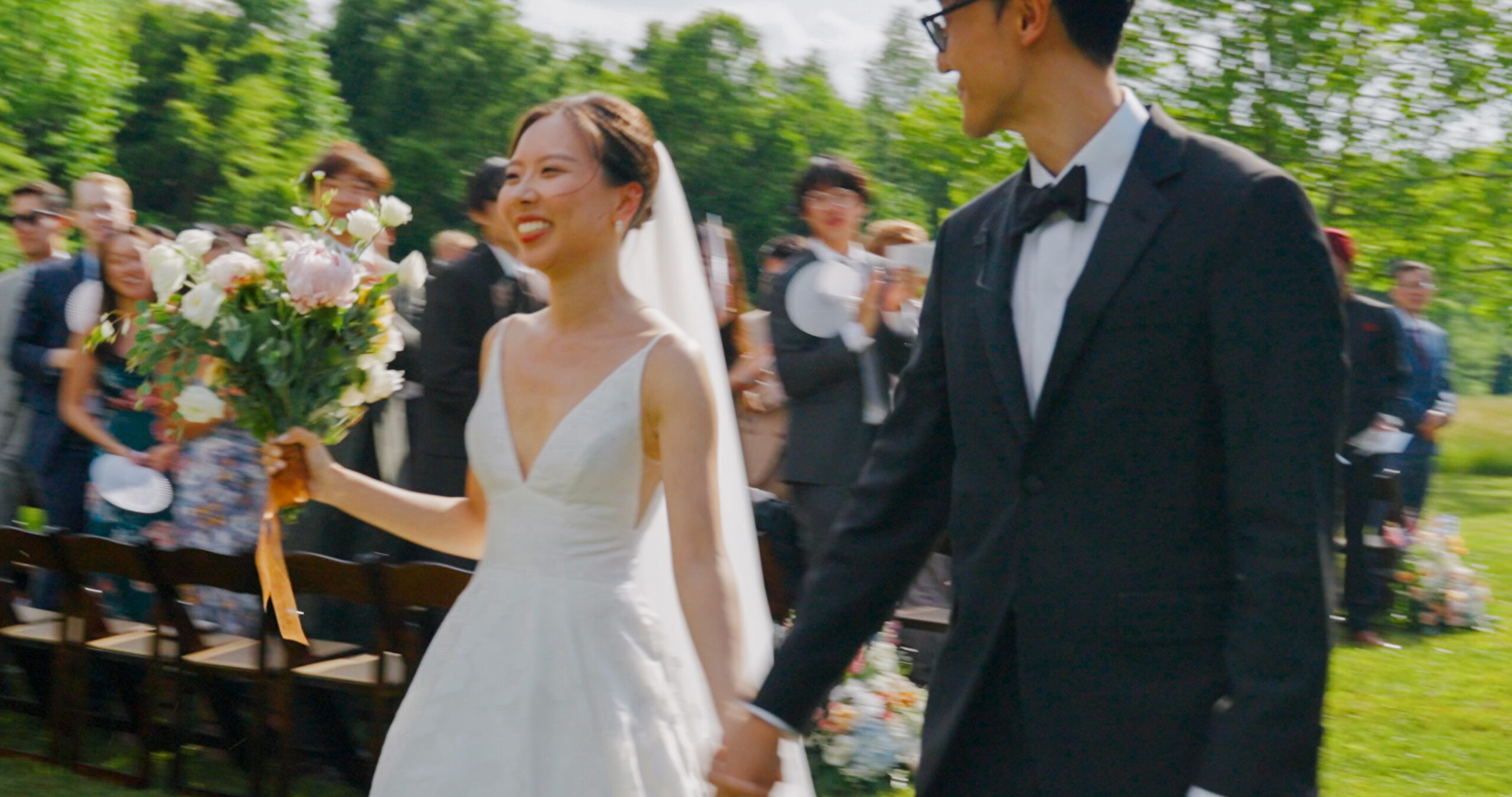 Christie and Hao smile and hold hands as they walk back down the aisle.