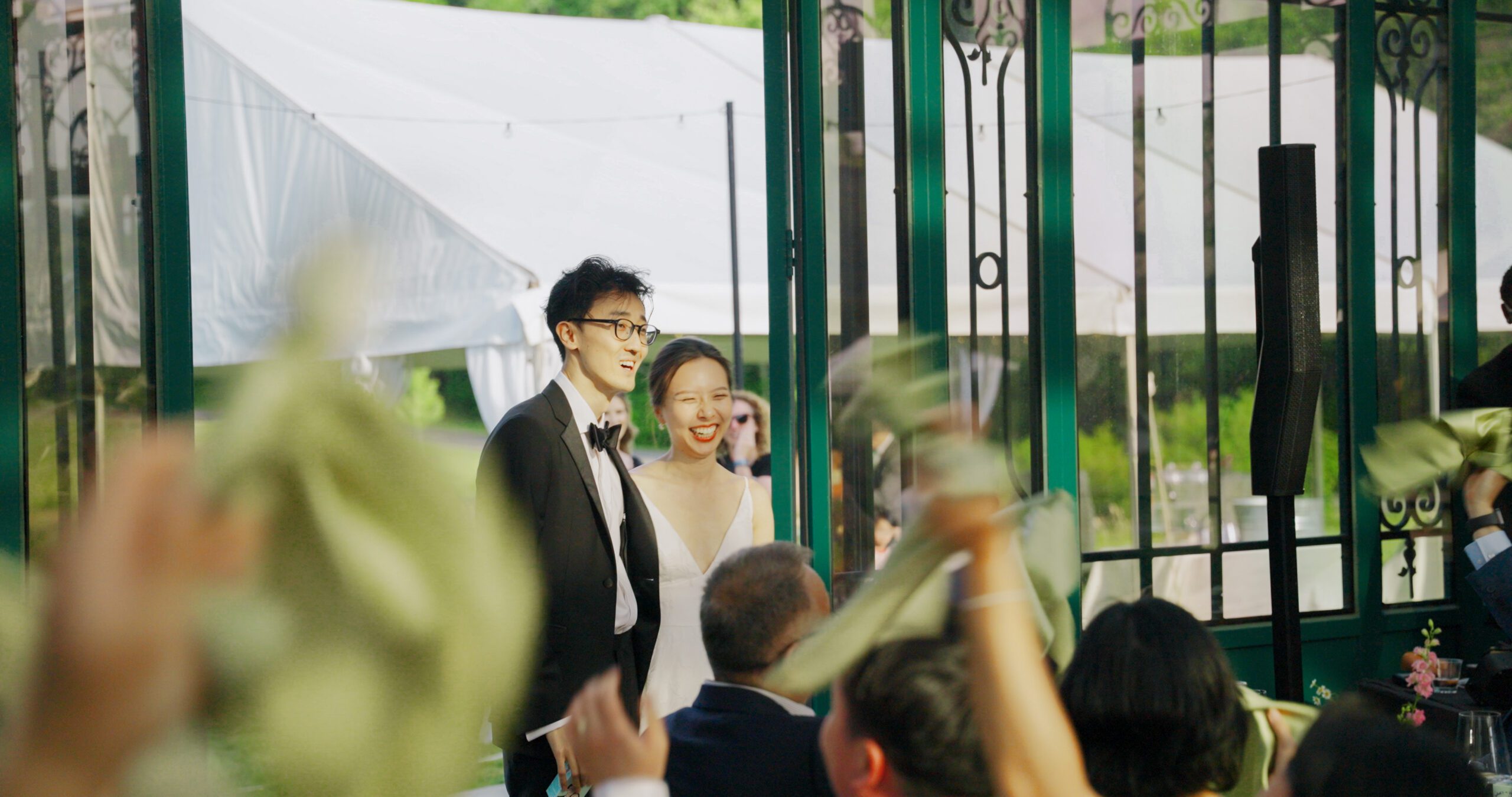 Christie and Hao enter their reception as guests celebrate around them.
