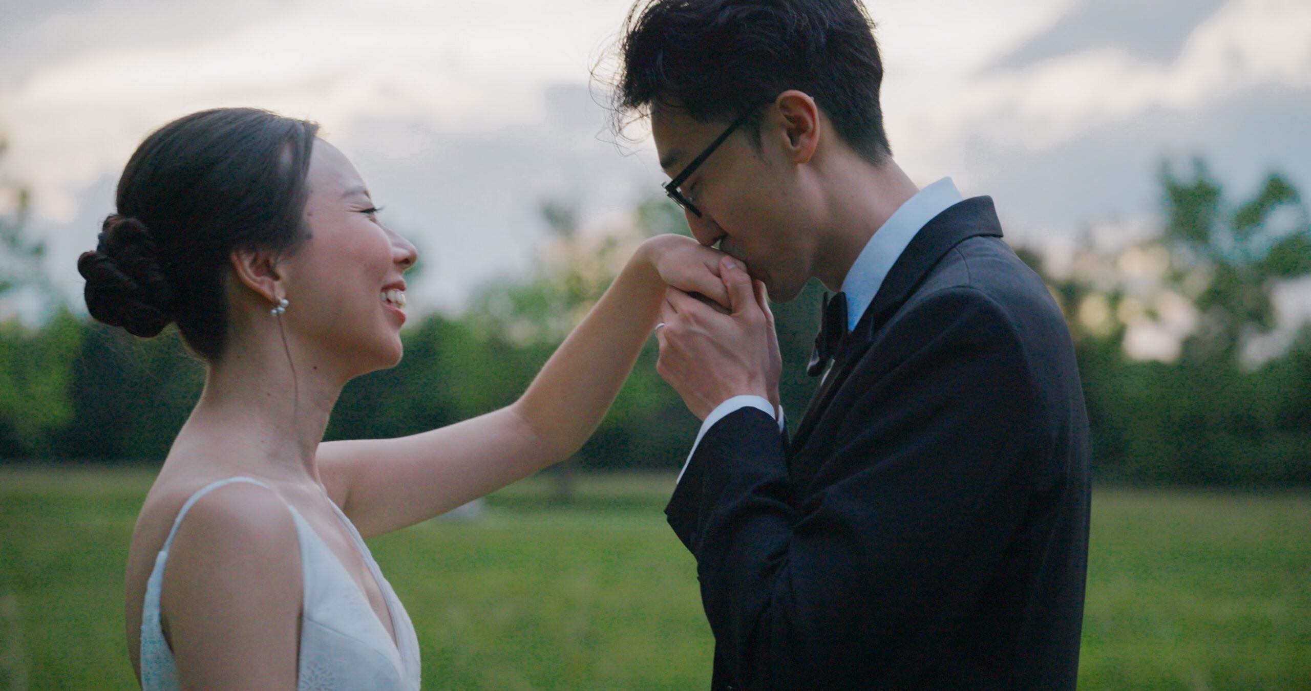 Hao kisses Christie’s hand as she laughs during their meadow portraits.