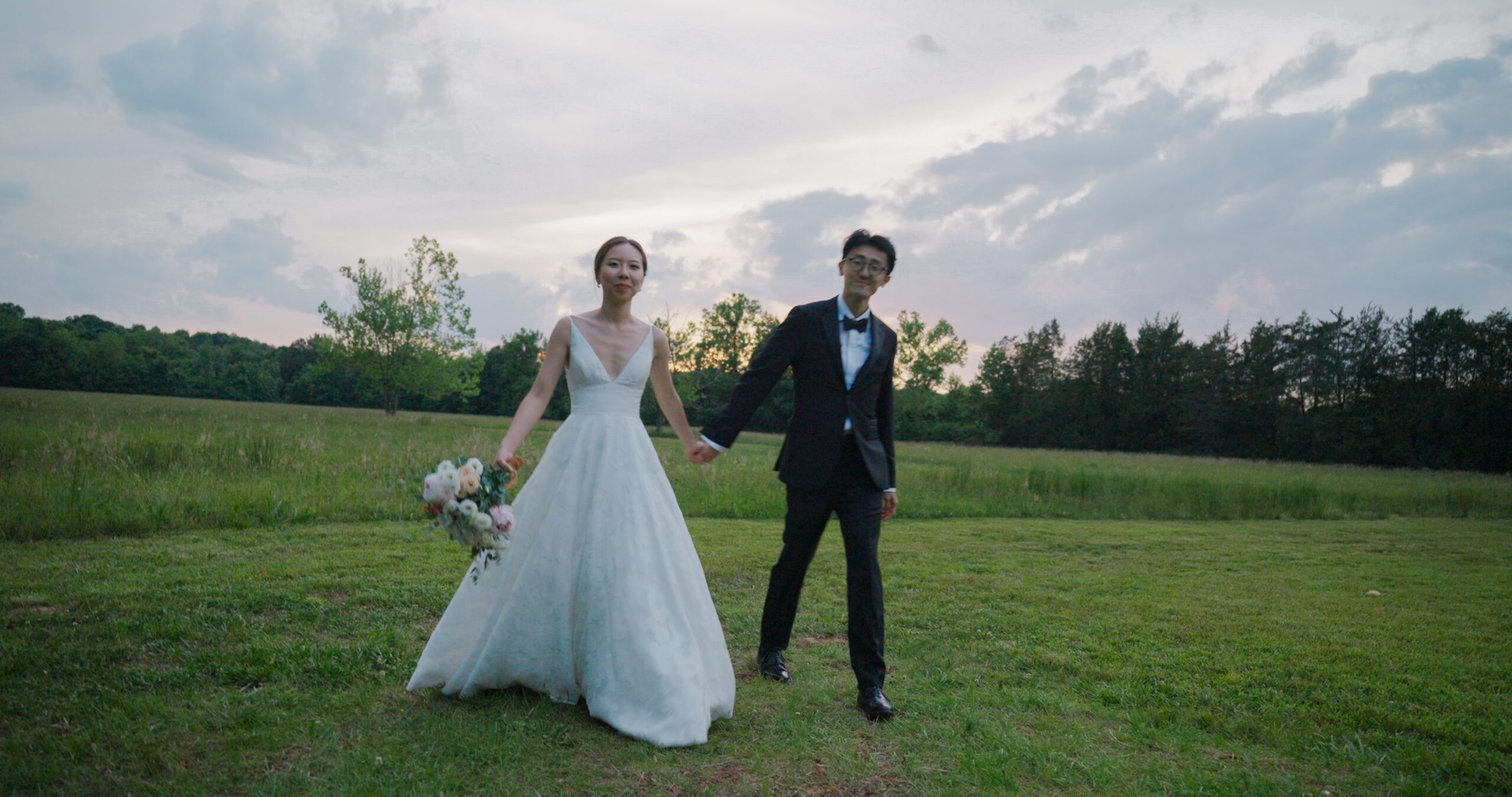 Christie and Hao walk hand in hand through the grass at Haven Ridge.