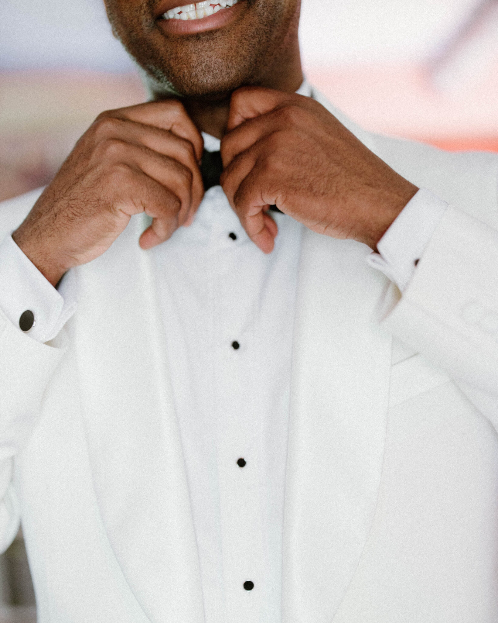 Groom getting ready and tying bowtie inside before wedding ceremony