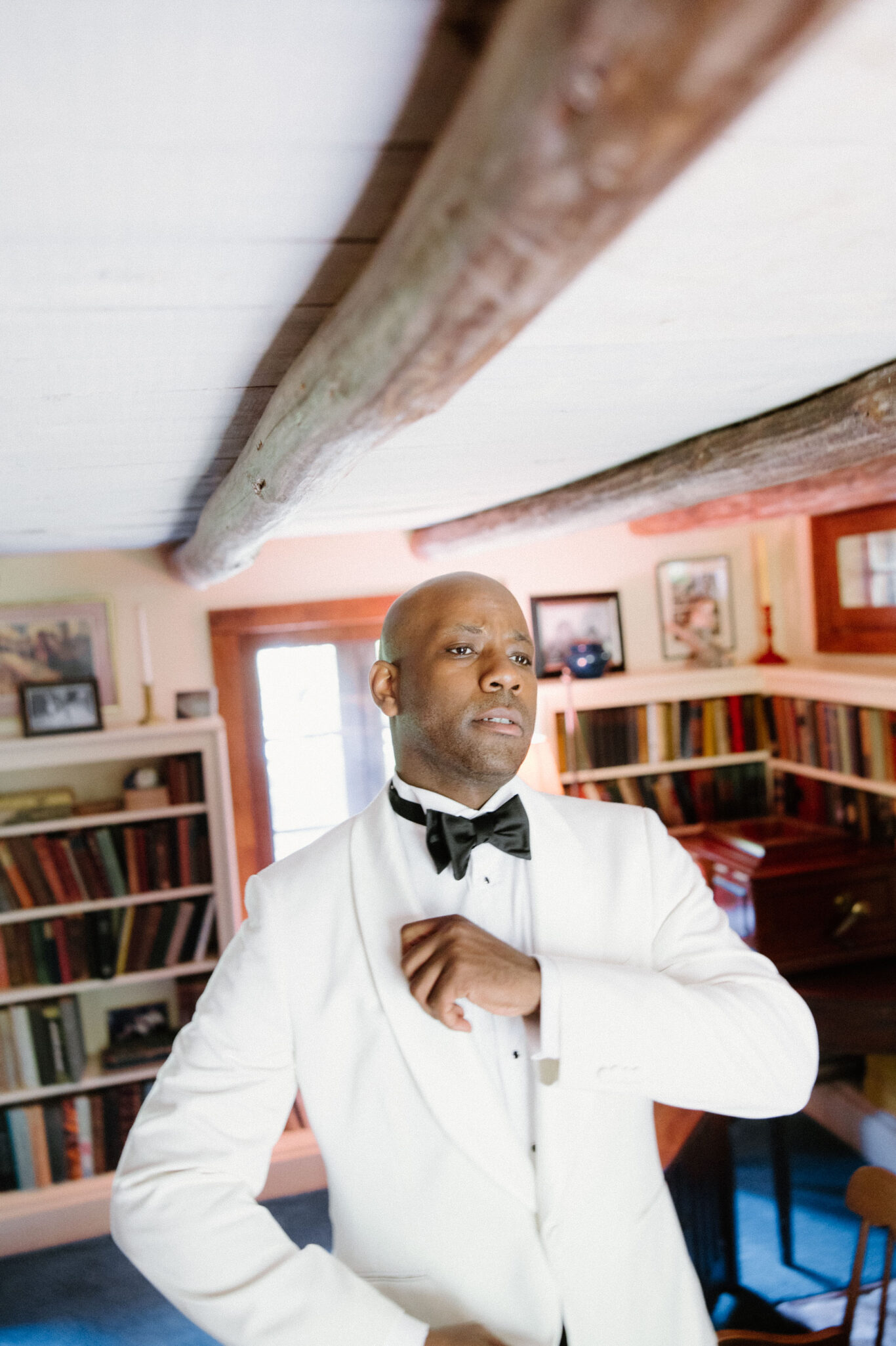 Groom getting ready and tying bowtie inside before wedding ceremony