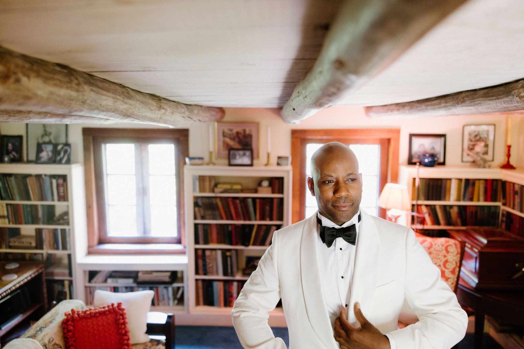 Groom getting ready and tying bowtie inside before wedding ceremony