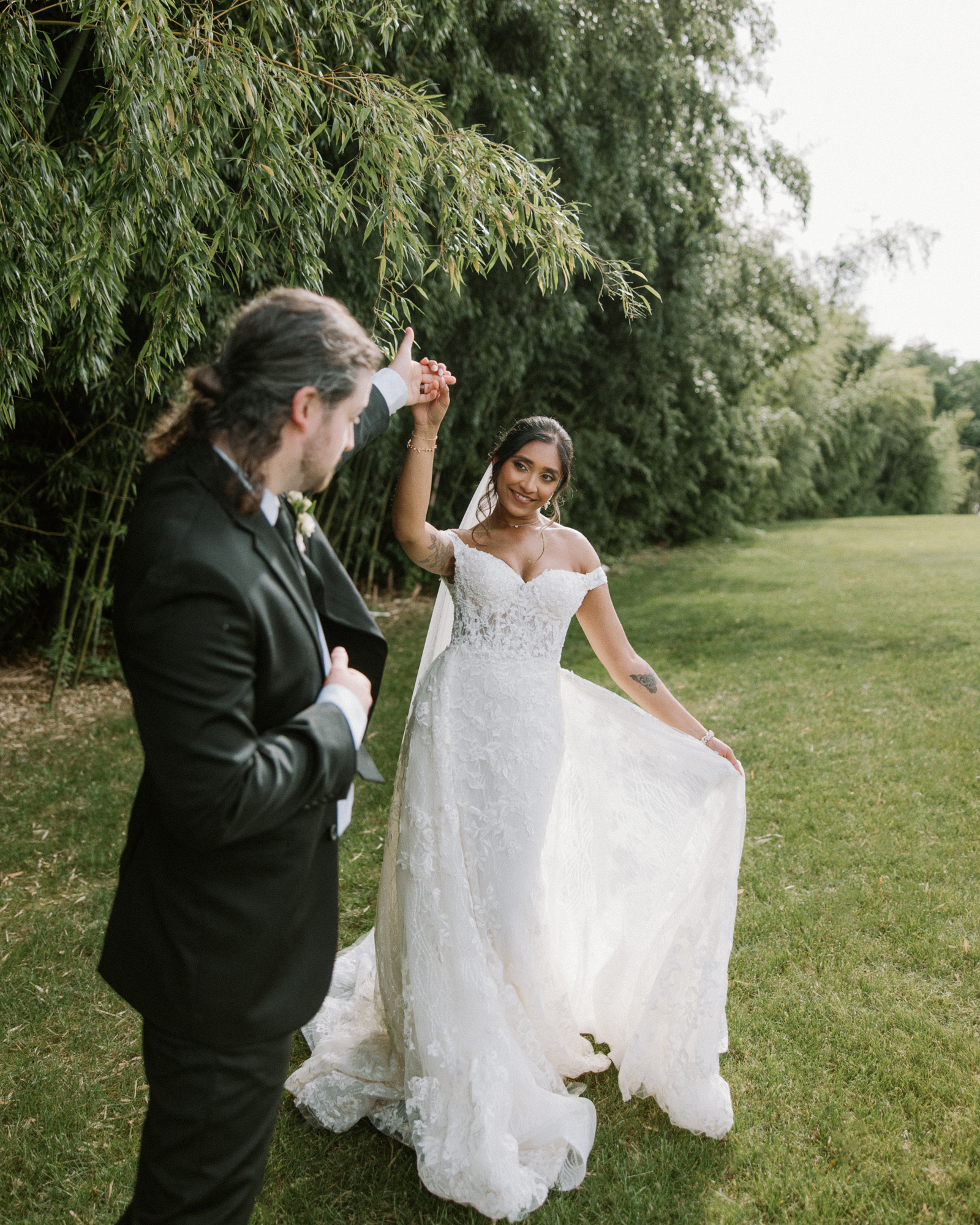 Bride and Groom dance in a green field in the sunlight. 