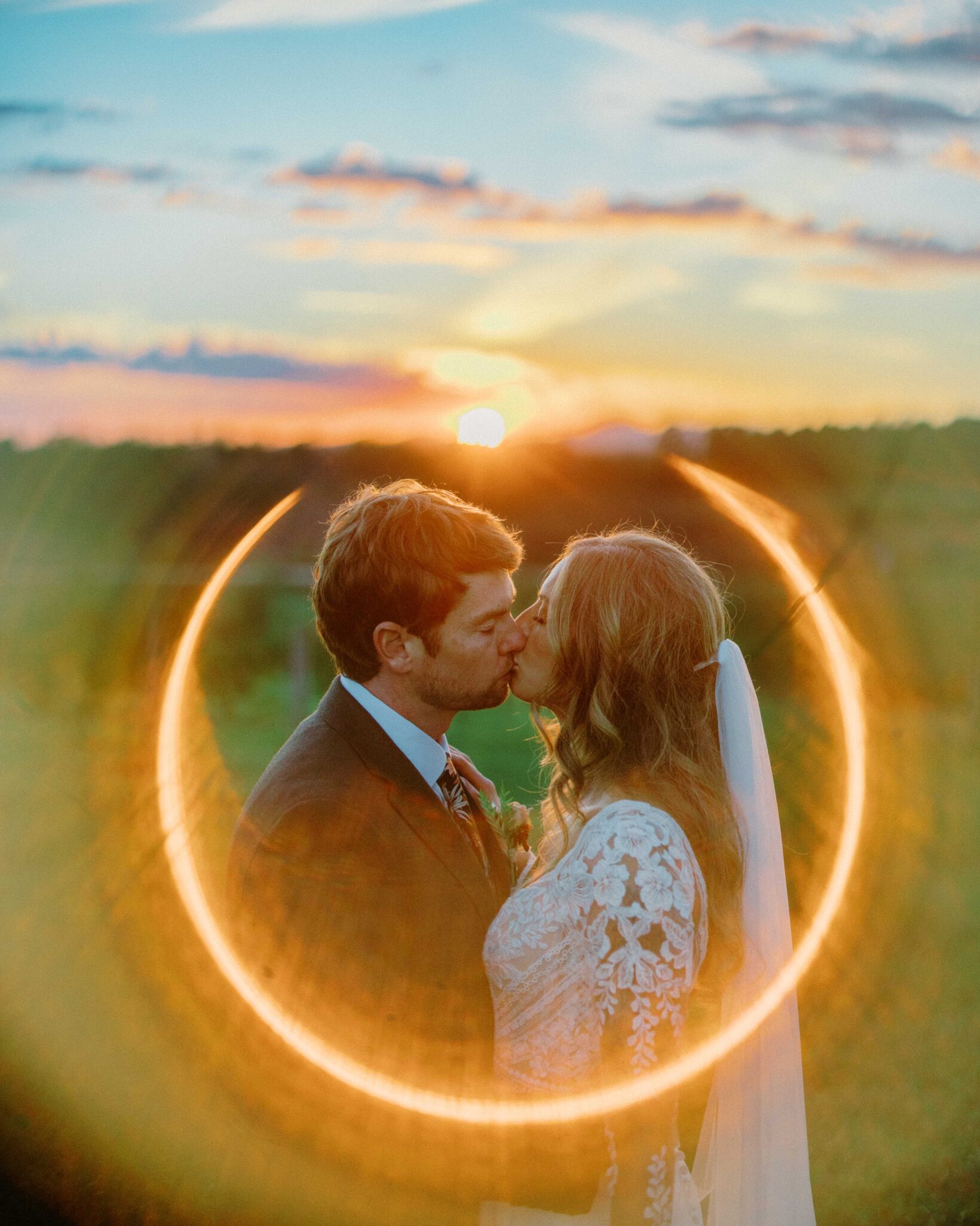 newlyweds kiss at sunset with a big sun flare. 