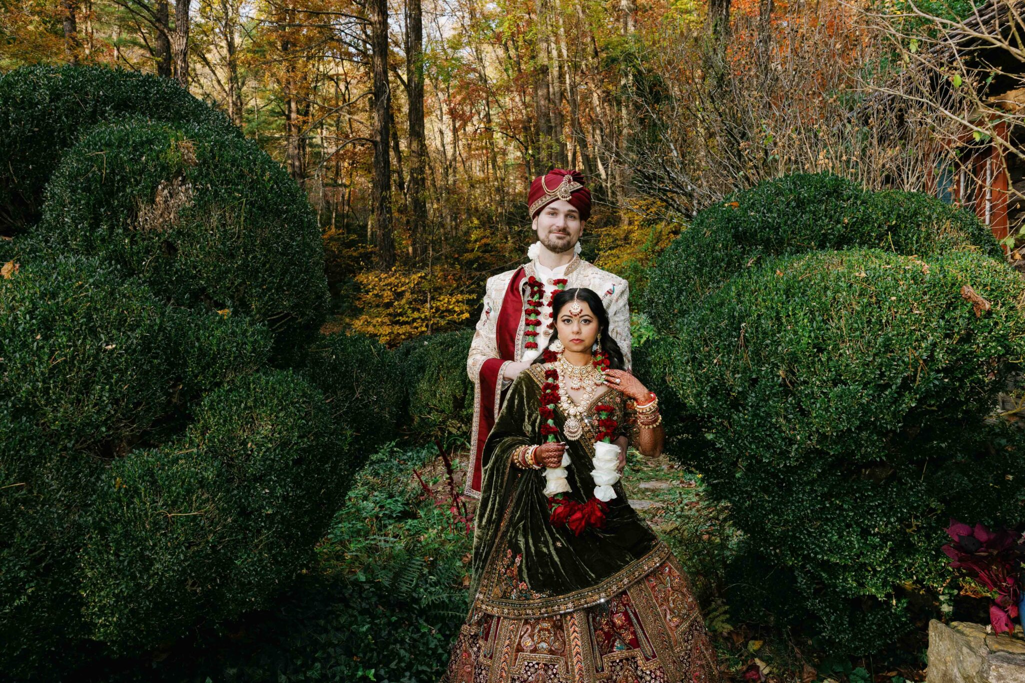 Cinematic couple’s portrait surrounded by spring color, mostly green, at an Asheville Indian wedding.